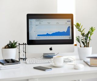 Silver Imac Displaying Line Graph Placed on Desk